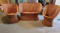 Full view of the three-piece wicker patio set including two chairs and a loveseat, placed on a concrete floor.