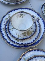 Close-up of one demitasse cup stacked on a saucer and dessert plate showing scalloped edges