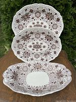 Three ironstone platters on wooden surface, showing overall size and pattern.
