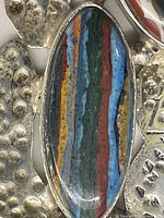 Close-up photo of the largest oval multi-colored striped stone inlay on the pendant.