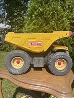 Side view showing yellow steel dumper body, large Tonka-labeled tires, and detailed construction.