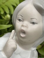 Close-up of the girl's face showing detailed expression and finger raised.