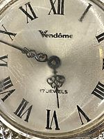 Close-up image of the watch face showing Roman numerals, ornate hands, 'Vendôme' branding, and '17 JEWELS' marking.