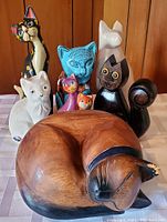 Front view of all seven cat statues arranged in two rows showing details, colors and wear.