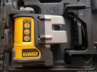 Top-side photo of DeWalt DW089 laser line tool showing yellow and black body with metal clamp attachment in plastic case.