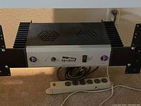 Front view of Hafler TA 1600 amplifier shows grey face panel with purple knobs, headphone input, power switch, ventilation on top, and large black heat sinks on sides.