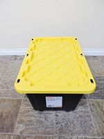 Front view of a single HDX tough tote with yellow lid on floor.
