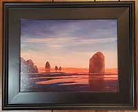 Full front view of the oil painting showing a moody ocean sunset with prominent rocks and a black frame.