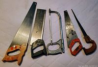 Photo showing five metal saws of various sizes and shapes for trades, condition used.