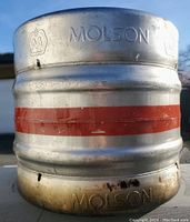 Close-up image of the Molson branded stainless steel round Sanke keg showing embossed Molson name, brand logo, and red stripe paint detail.