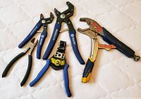 Eight assorted vice grips and pliers on white surface showing different styles and handles including locking pliers, wire cutters, and wire stripper.
