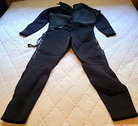 Full body view of the black wetsuit laid flat on a surface showing front side and length of sleeves and legs.