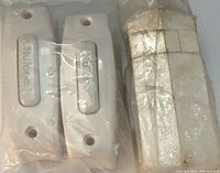 Four white rectangular doorbell buttons with two mounting holes each, two are branded Nutone and two are unbranded, shown inside clear plastic packaging with adhesive residue.