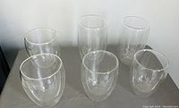 Photo showing six clear double-walled glass tumblers arranged in two rows of three on a flat surface.