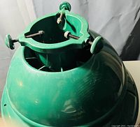 Photo of green plastic Christmas tree stand showing top tightening screws and round water reservoir base.