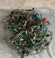 Photo of four strands of tangled Christmas lights with varied colored bulbs (red, green, yellow, blue) and green wiring.