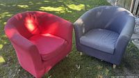 Photo shows two IKEA club chairs outdoors on grass, one red fabric and one grey faux leather.