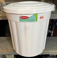 White Mistral branded locking lid for waste can with label in English and French, shown standing on a shelf.