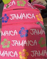 Close-up of pink purse featuring 'Jamaica' text with colorful hibiscus flowers and two visible zippers.