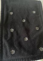 Close-up image showing black scarf fabric with white snowflake patterns distributed across it.