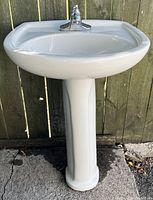 Front view of white ceramic pedestal sink with pedestal base and chrome single lever tap