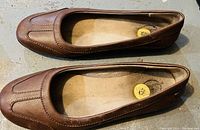 Top view of brown ladies dress shoes size 8 laid out on a concrete surface.