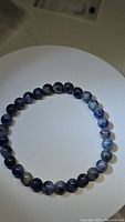 Blue sodalite stretchy bracelet laid flat to show entire circular shape and bead colors.
