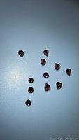 Image showing 12 natural deep reddish-brown almandine garnet gemstones arranged loosely on a surface, highlighting their bullet-shaped faceted cut.