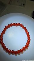 Close-up photo of polished round carnelian beads forming a stretchy bracelet.