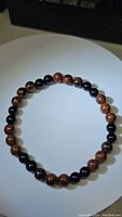 Front side view of stretchy bracelet showing alternating mahogany jasper and black onyx beads.