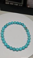 Natural turquoise bracelet with round robin's egg blue beads arranged in a circle on a white surface