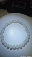 Photo of natural white jade bead bracelet displayed on flat surface, showing round polished white beads.