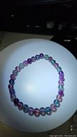 Top view of natural rainbow fluorite beaded elastic bracelet showing translucent multicolored round beads arranged in a circle.