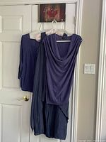 Blue boho dress with two blue casual tops hanging on a door, showcasing layers and styles