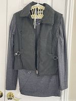 Grey DYNA zippered vest layered over grey knit long-sleeve top with smooth and knit fabric combined, hanging on a hanger.