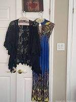 Photo of multi-coloured halter dress hanging with black lace jacket on a door.
