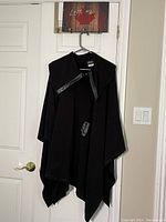 Front view of black Artex poncho with faux leather trim on collar and closure details.