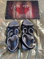 Top-view photo showing the pair of Clarks black and gray sandals with adjustable Velcro ankle straps and textured footbeds.