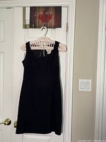 Full view of navy blue faux suede sheath dress hanging on a hanger against a door background