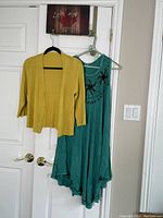 Photo showing the yellow cardigan and turquoise dress hanging on door, displaying colors and styles clearly.