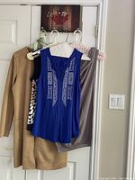 Photo showing entire lot including the camel suede coat and two tops hanging on hangers.