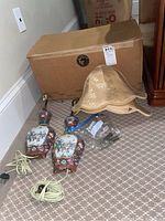 Photo showing the pair of lamps with cords coiled beside a cardboard box, two fabric lampshades stacked with one showing a tear.