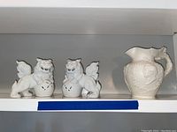 Full view of Copeland vase with handle and two white Asian dragon figures on shelf