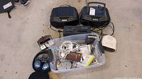 Overview photo showing two Sony Dream Machine units, micro cassette recorder, digital audio recorder, Bose headphones with blue ear cushions, Sony Discman and multiple cables in plastic bin.