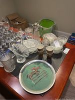 Overview of the glassware including pitchers, bowls, candy jar, and platters on a wooden table.
