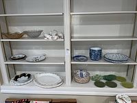 Shelves displaying various dishes including glass bowls, white and blue china plates, and serving trays.