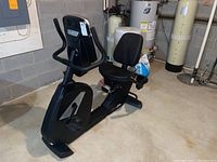 Side angle view of the Sole R92 stationary recumbent bike showing the full length, padded seat and back support, pedal, and part of the console. The bike is black and appears clean with minor use.
