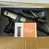 Photo of Anova Precision Cooker immersion circulator and accessories inside box with user manual