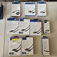 Photo of all Insignia cables and adapter in original packaging laid out on table, showing various connectors and product details on boxes.