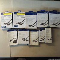 Top down view of 11 Insignia boxed HDMI and DisplayPort adapter and cable packages arranged on a tabletop.